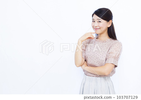 A woman in her thirties thinking with a smile in front of a white background 103707129
