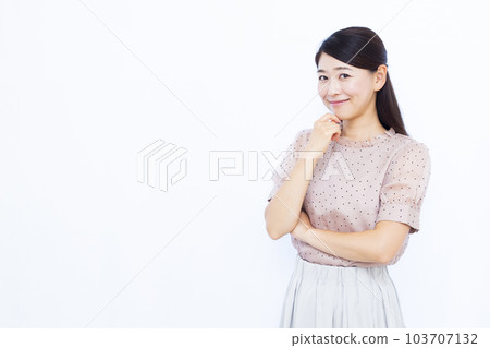 A woman in her thirties thinking with a smile in front of a white background 103707132
