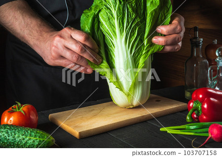 A professional chef makes a fresh napa cabbage salad. Preparation for slicing in the restaurant kitchen. Vegetable diet idea 103707158