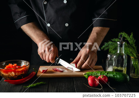 Chef cuts radishes in a vegetable salad. Cooking delicious salad in the kitchen of a restaurant or cafe Chef cuts radishes in a vegetable salad. Cooking delicious salad in the kitchen of a restaurant or cafe 103707225