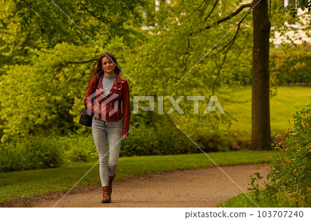 Hipster girl in leather jacket walking in the park Hipster girl in leather jacket walking in the park 103707240