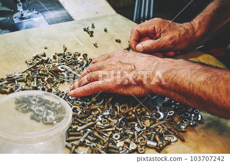 Hands of a craftsman mechanic choose the right bolt nut for repair Hands of a craftsman mechanic choose the right bolt nut for repair 103707242