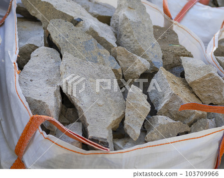 Construction mounds. Large white bag with handles filled with various types of pebbles or cobblestones Construction mounds. Large white bag with handles filled with various types of pebbles or cobblestones 103709966