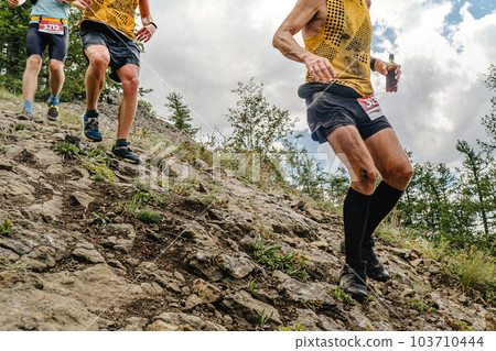 group athletes runners running down steep mountainside, summer trail marathon race group athletes runners running down steep mountainside, summer trail marathon race 103710444