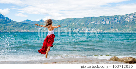 Woman in red dress jumping at the lake Woman in red dress jumping at the lake 103712030