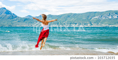 Woman in red dress jumping at the lake Woman in red dress jumping at the lake 103712035