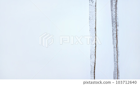 Two icicles with light blue overcast sky in background. Wide banner, space for text left side. Two icicles with light blue overcast sky in background. Wide banner, space for text left side. 103712640