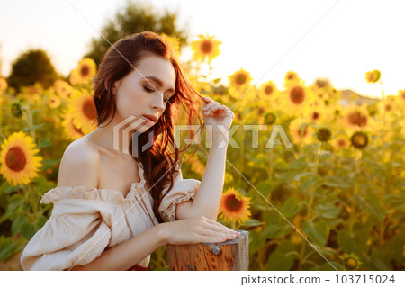 Beautiful woman in a dress in a field of sunflowers 103715024