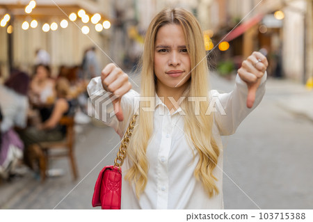 Upset young woman girl showing thumbs down sign, disapproval, dissatisfied bad work, mistake in city Upset young woman girl showing thumbs down sign, disapproval, dissatisfied bad work, mistake in city 103715388