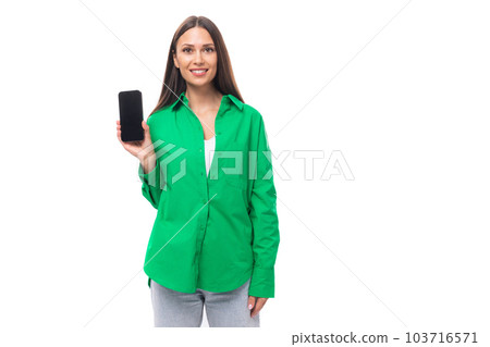 slender young brown-haired female model with brown eyes in a green shirt shows the screen of a 103716571
