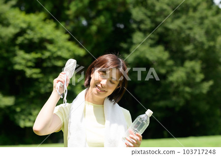 Woman using a fan outdoors 103717248