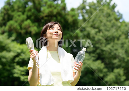 Woman using a fan outdoors Woman using a fan outdoors 103717250