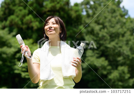 Woman using a fan outdoors Woman using a fan outdoors 103717251