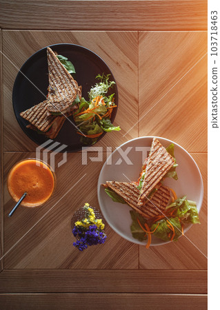 toasted vegetarian sandwich with mozzarella cheese and tomato and orange juice 103718463