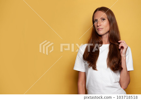 Portrait of mid adult woman standing on yellow background 103718518
