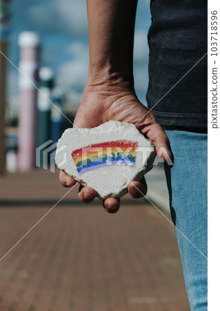 man with a rock with a rainbow flag on the street 103718596