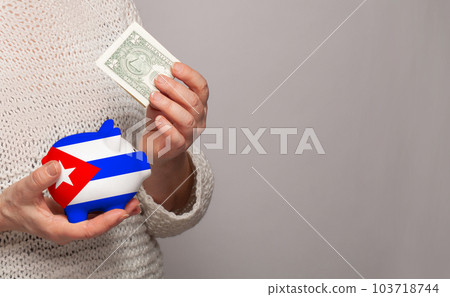 Flag of Cuba on money bank in Cuban woman hands. Flag of Cuba on money bank in Cuban woman hands. 103718744