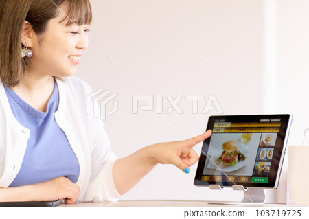A female customer ordering food on a touch panel 103719725