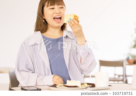 一個年輕女人吃著蛋糕，表情很美味 103719731