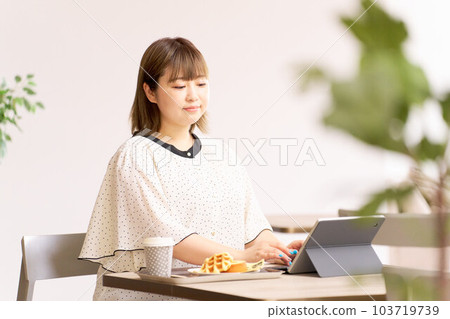 A young woman working on a computer while eating at a cafe 103719739