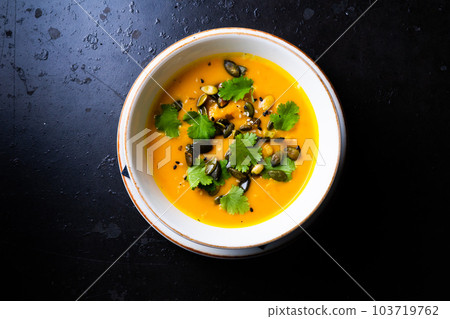 Pumpkin and carrot soup with cream and parsley on dark wooden background Pumpkin and carrot soup with cream and parsley on dark wooden background 103719762