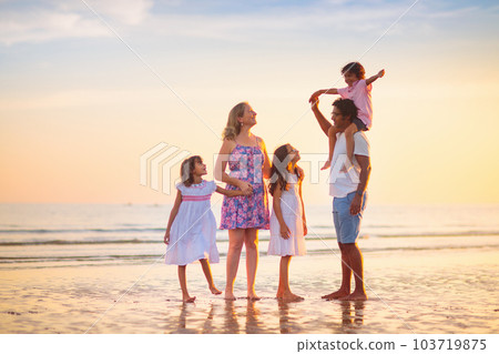 Family walking on tropical beach at sunset Family walking on tropical beach at sunset 103719875