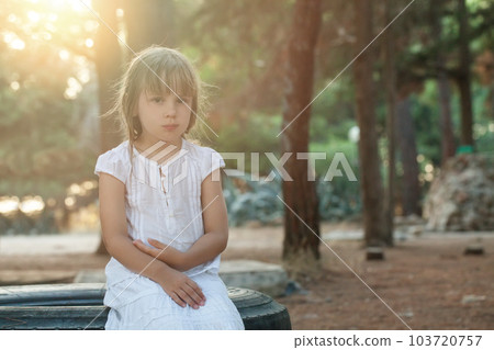 Cute brunette child girl in white clothes sitting on the tire  in the park 103720757