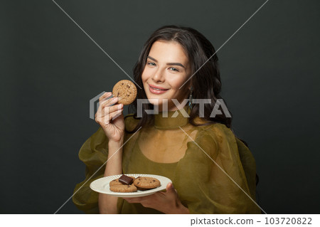 Lovely happy woman with cookies against black studio wall background 103720822