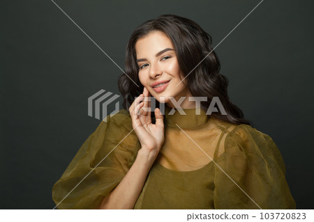 Cute woman smiling against black studio wall background 103720823
