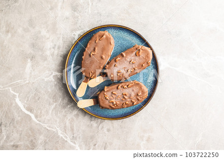 Popsicle, ice cream covered with chocolate on plate. Top view. Popsicle, ice cream covered with chocolate on plate. Top view. 103722250