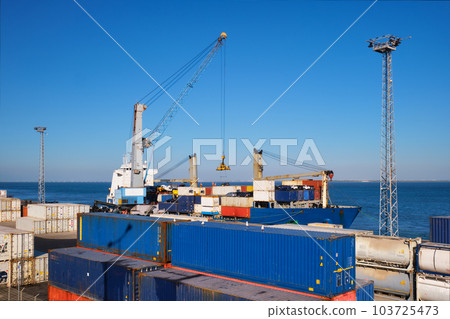 Port crane loading commercial container ship with cargo containers and cars in industrial sea port. Lisbon, Portugal 103725473