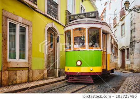 Famous vintage yellow tram 28 in the narrow streets of Alfama district in Lisbon, Portugal - symbol of Lisbon, famous popular travel destination and tourist attraction 103725480