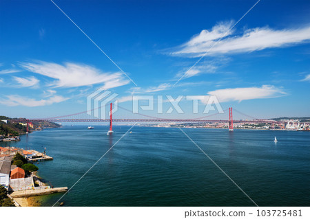 View of 25 de Abril Bridge famous tourist landmark of Lisbon connecting Lisboa to Almada on Setubal Peninsula over Tagus river with boats yachts and vessels. Lisbon, Portugal View of 25 de Abril Bridge famous tourist landmark of Lisbon connecting Lisboa to Almada on Setubal Peninsula over Tagus river with boats yachts and vessels. Lisbon, Portugal 103725481