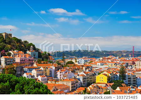 Lisbon famous view from Miradouro dos Barros tourist viewpoint over Alfama old city district with St. George's Castle and Portugal flag, 25th of April Bridge, Christ the King statue. Lisbon, Portugal. Lisbon famous view from Miradouro dos Barros tourist viewpoint over Alfama old city district with St. George's Castle and Portugal flag, 25th of April Bridge, Christ the King statue. Lisbon, Portugal. 103725485