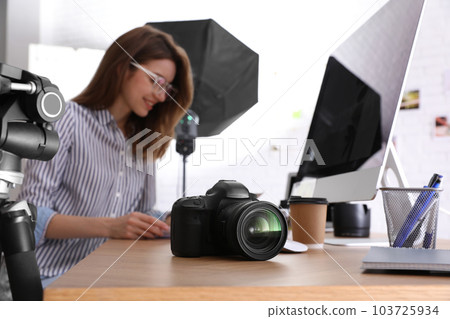 Professional photographer working at table in office, focus on camera 103725934