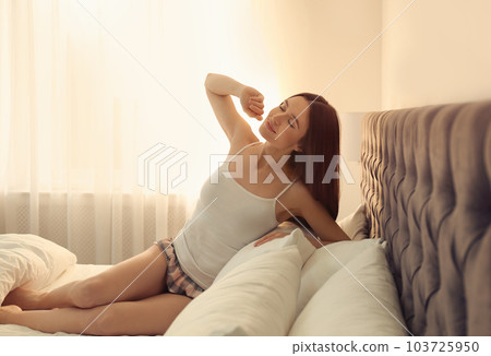 Young woman stretching on bed at home. Lazy morning 103725950