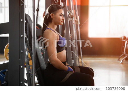 Young woman in sportswear resting in modern gym Young woman in sportswear resting in modern gym 103726008