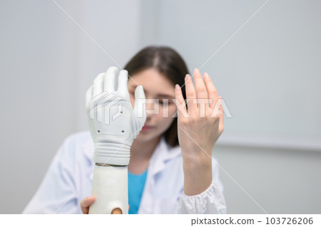Technician testing robotic bionic arm at prosthetic manufacturing Technician testing robotic bionic arm at prosthetic manufacturing 103726206