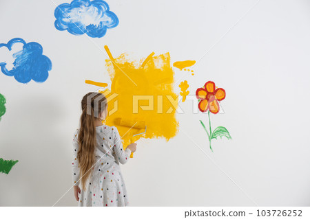 Little child painting wall with roller brush indoors 103726252
