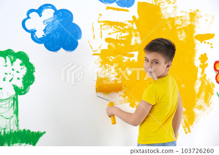 Little child painting wall with roller brush indoors 103726260