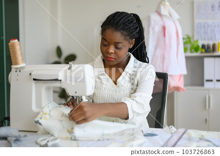 Happy dressmaker designer working in workshop studio Happy dressmaker designer working in workshop studio 103726863