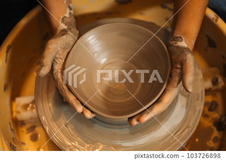 Close up on skillful hands sculpting pottery jar on potter wheel Close up on skillful hands sculpting pottery jar on potter wheel 103726898