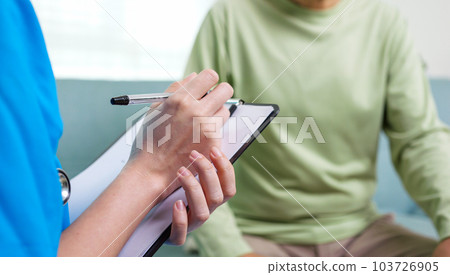 Caregiver nurse taking care of elderly grandfather sitting on sofa at home 103726905