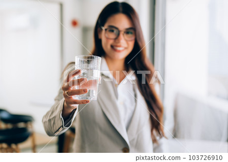 Female businesswoman holding glass of water at office 103726910