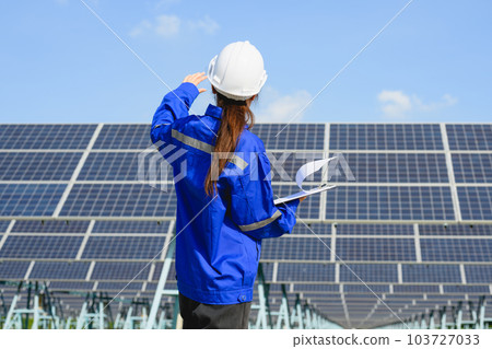 Female engineer worker with solar panels at solar farm 103727033