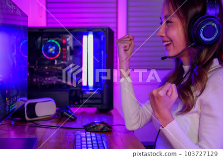 Young woman wearing headphones playing computer game Young woman wearing headphones playing computer game 103727129