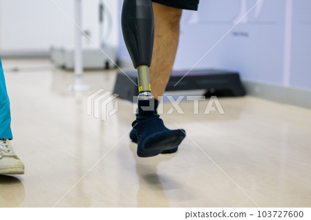 Physiotherapist helping patient with prosthetic leg at parallel bars Physiotherapist helping patient with prosthetic leg at parallel bars 103727600