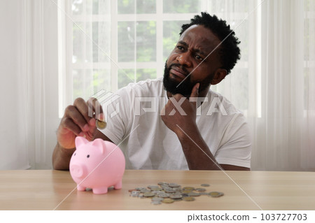 Man putting coin of cash into ceramic piggy bank 103727703