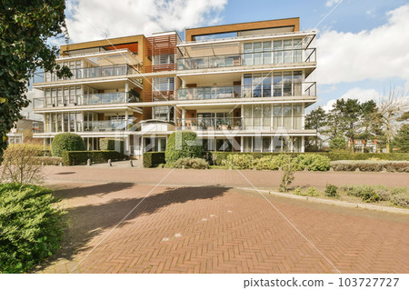 a large house with many windows and bales on the top floor there is a brick paved driveway in front 103727727