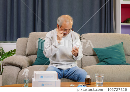 Senior man looking and reading label of medicine at home Senior man looking and reading label of medicine at home 103727826